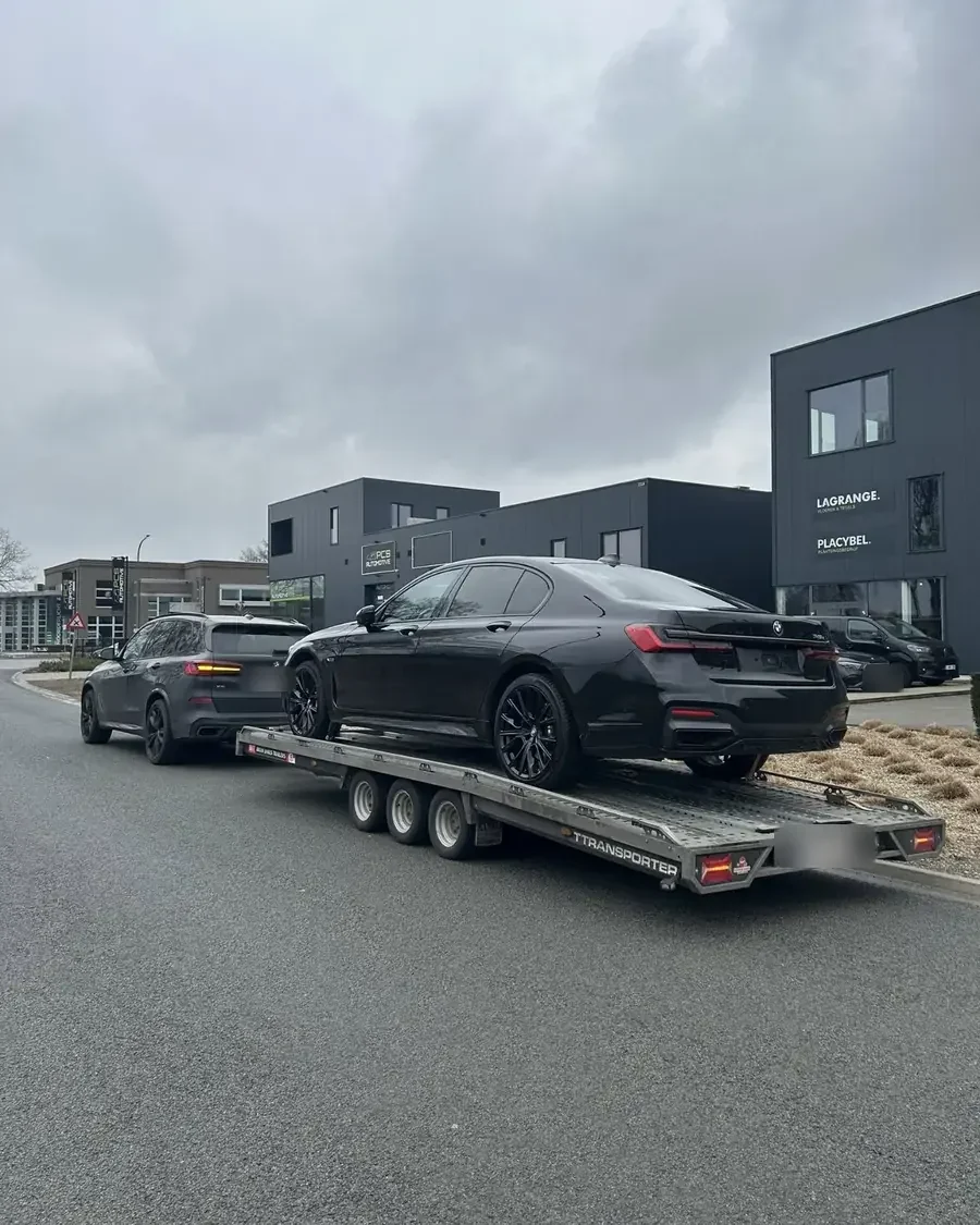 Zwarte BMW op de autotrailer van CLIM tijdens het transport van een wagen uit Duitsland